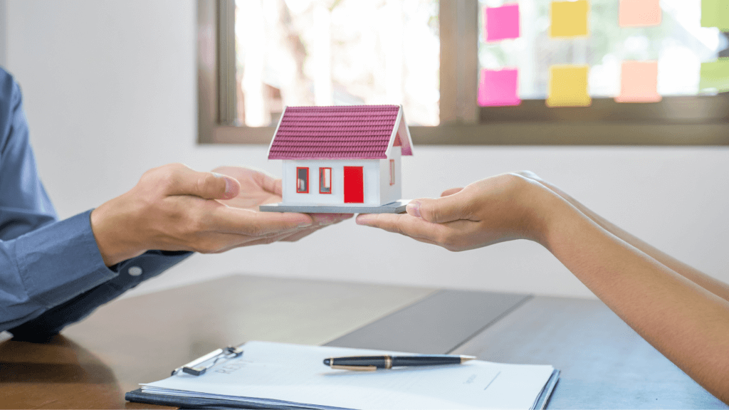 Personne tenant une maison miniature symbolisant une promesse d'achat